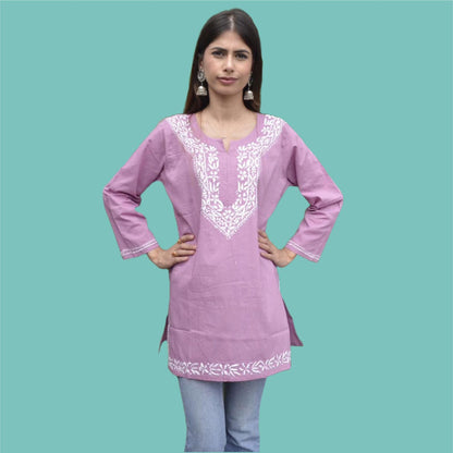 A woman wearing a light purple chikankari cotton short top with embroidery on the chest and sleeves, paired with blue jeans.